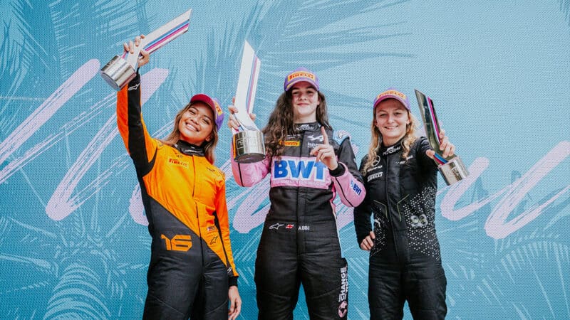 Abbi Pulling holds up winners trophy from F1 Academy 2024 Miami round with Bianca Bustamante and Doriane Pin on either side
