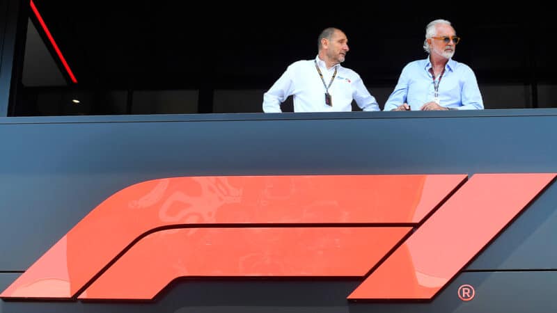 Bruno Michel and Flavio Briatore stand on a balcony above an F1 sign