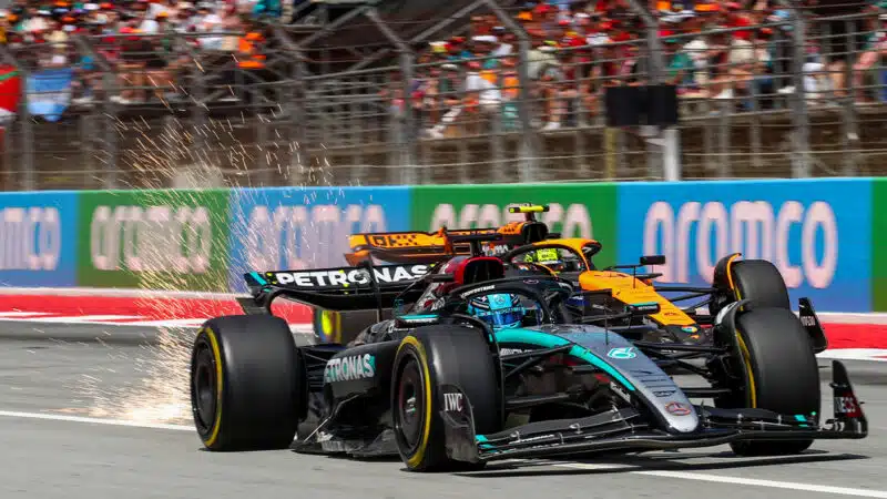 Sparks fly from the Mercedes of George Russell as he defends against the McLaren of Lando Norris in 2024 F1 Spanish GP