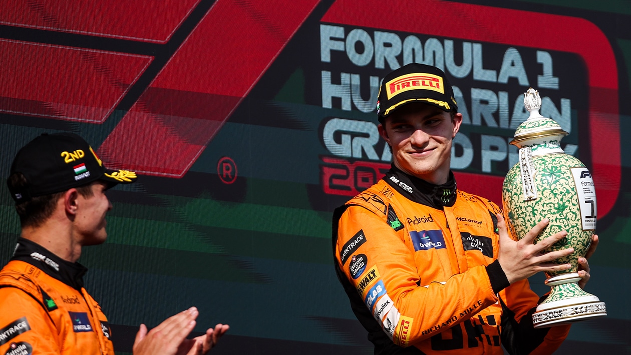 Oscar Piastri looks over to Lando Norris while holding the winning trophy from 2024 Hungarian GP