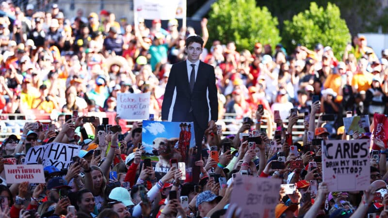 Crowd of United States Grand Prix fans holding a cutout of Charles Leclerc