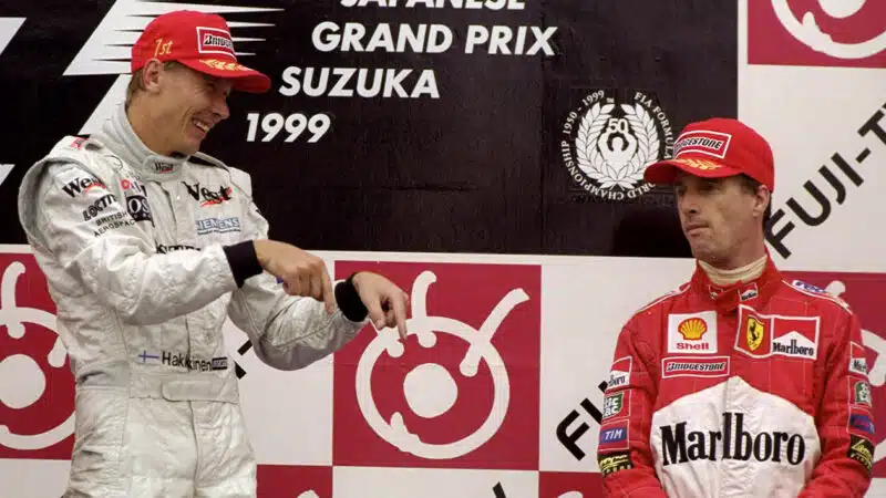 Mika Hakkinen points down towards Eddie Irvine on the podium after winning the 1999 F1 championship at the Japanese Grand Prix