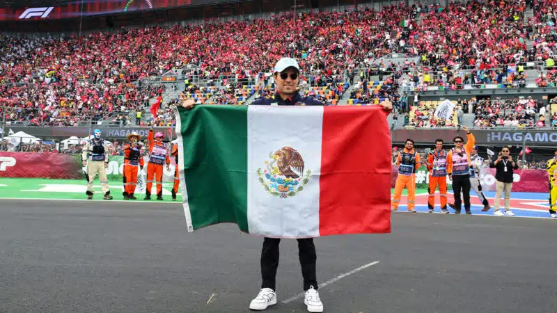 Sergio Perez with Mexican flag in front of fans at the 2024 F1 Mexican Grand Prix