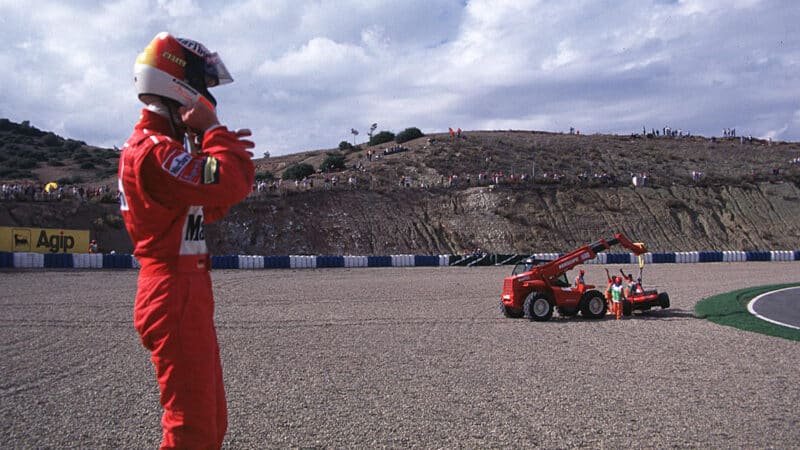 Michael Schumacher watches as his Ferrari F1 car is lifted out of gravel trap in 1997 European GP