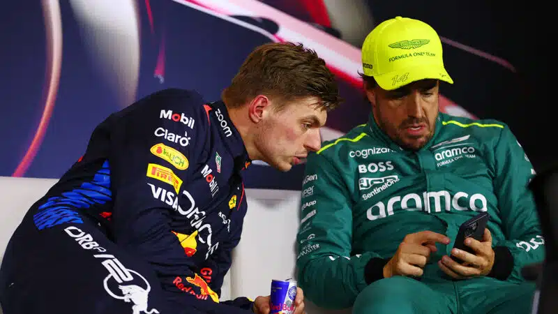 Max Verstappen and Fernando Alonso look at phone