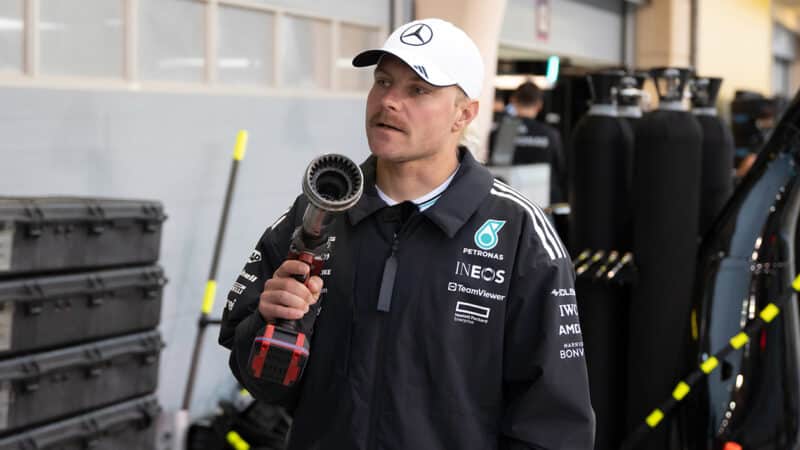 Valtteri Bottas holds F1 wheel gun next to Mercedes pit