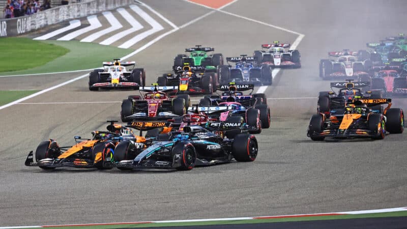 Oscar Piastri (McLaren-Mercedes) and George Russell (Mercedes) lead the field into the first corner after the start of the 2025 Bahrain Grand Prix.