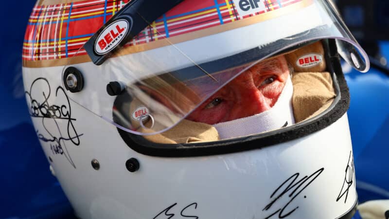 Jackie Stewart wearing helmet signed by F1 world champions
