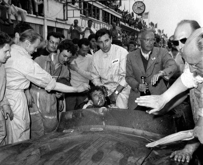 Shelby with cigarette behind the wheel with Salvadori
