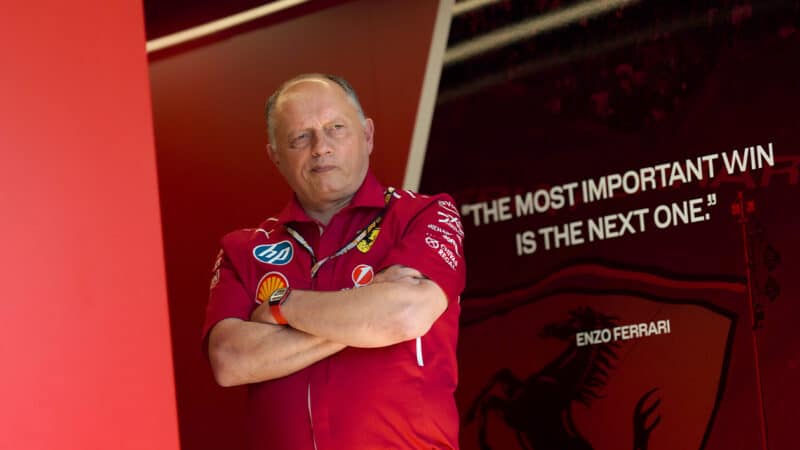 Fred Vasseur stands next to a quote in Ferrari F1 pit garage saying The most important win is the next one