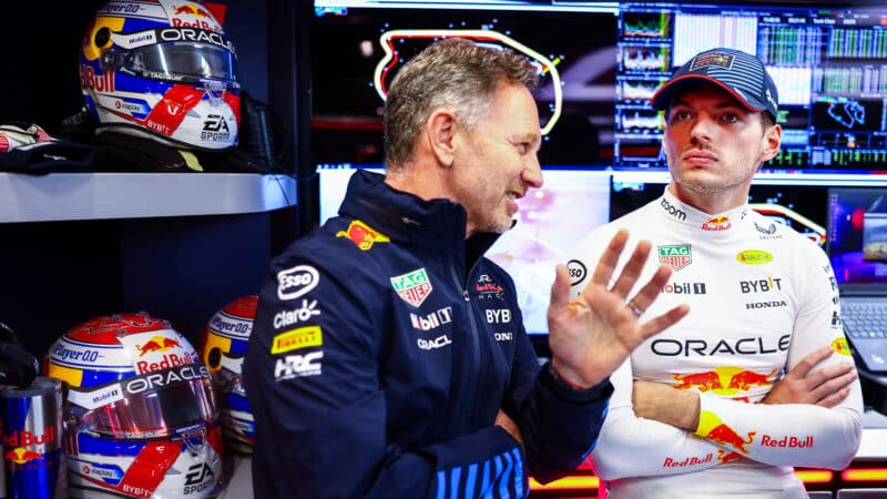 Christian Horner talks to a distracted looking Max Verstappen in the Red Bull F1 pit garage