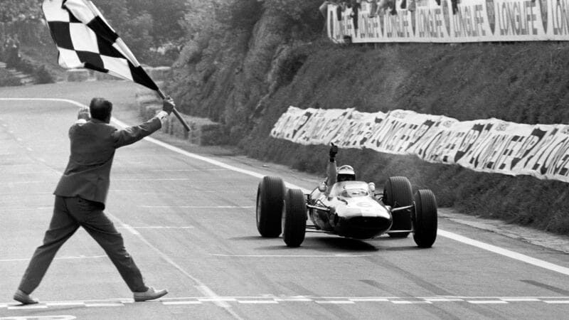 Jim Clark raises his hand as he crosses the line to win the 1965 F1 French Grand Prix at Clermont Ferrand